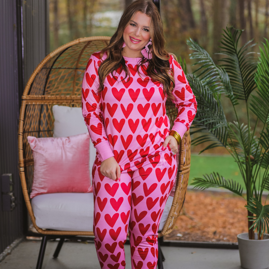 long-sleeve top with red hearts on a solid pink fabric and a rounded neckline paired with matching elastic waistband bottoms