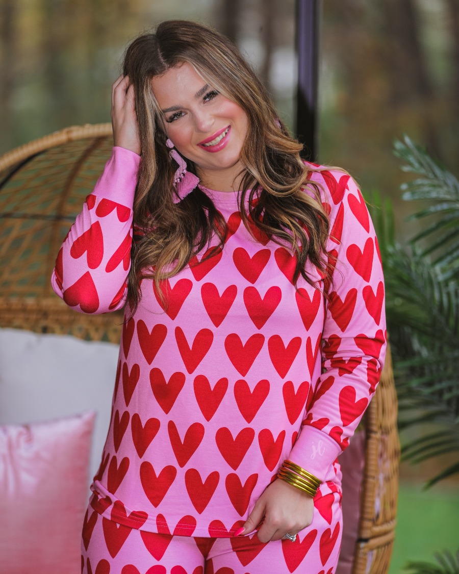long-sleeve top with red hearts on a solid pink fabric and a rounded neckline paired with matching elastic waistband bottoms