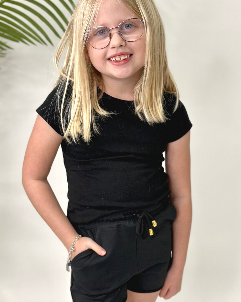 mid-rise relaxed fit activewear shorts with side pockets and a tie waist drawstring with gold bead accents, designed on a solid black print fabric and black trim