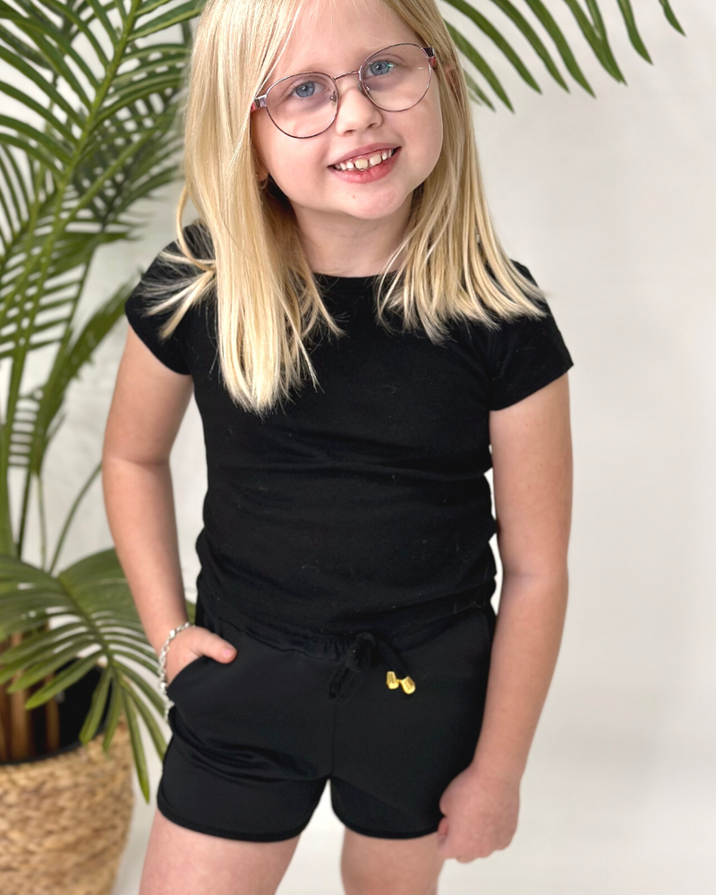 mid-rise relaxed fit activewear shorts with side pockets and a tie waist drawstring with gold bead accents, designed on a solid black print fabric and black trim