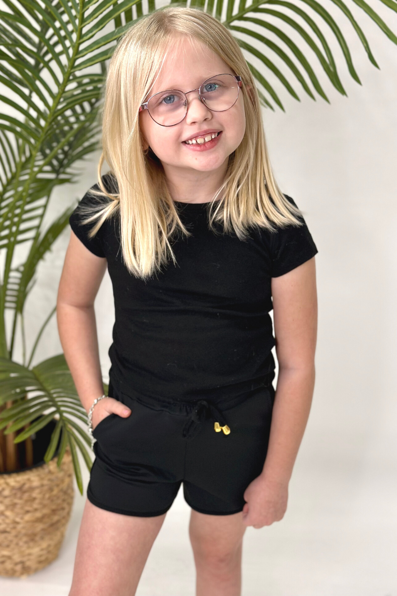 mid-rise relaxed fit activewear shorts with side pockets and a tie waist drawstring with gold bead accents, designed on a solid black print fabric and black trim