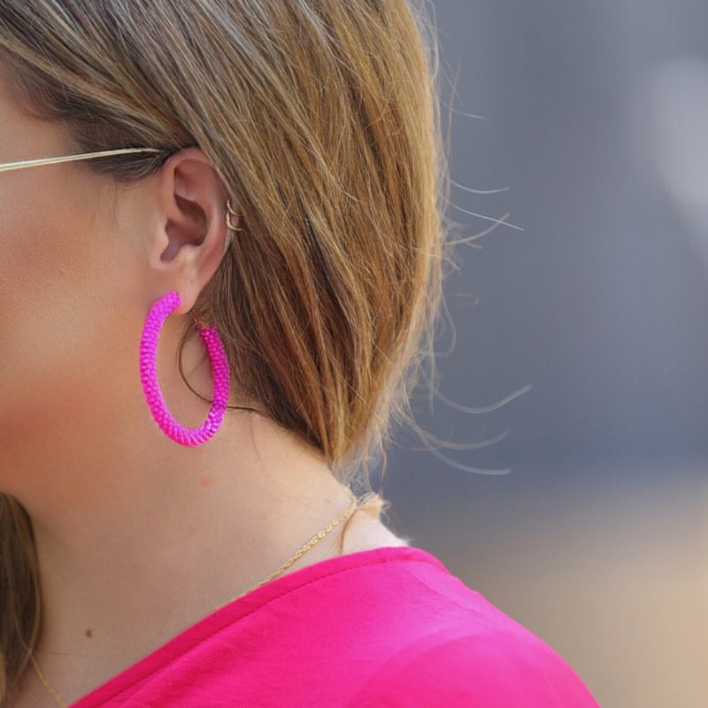 lightweight beaded hoop earrings with a classic circular silhouette in vibrant pink