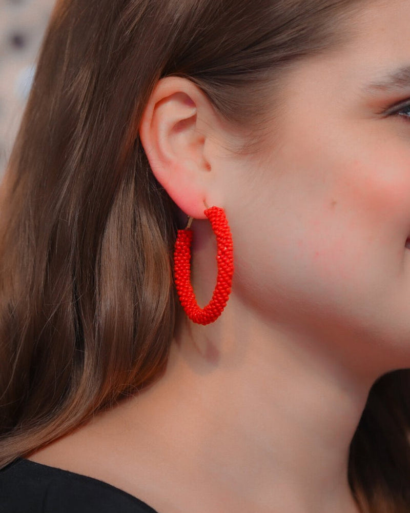 lightweight beaded hoop earrings with a classic circular silhouette in vibrant red
