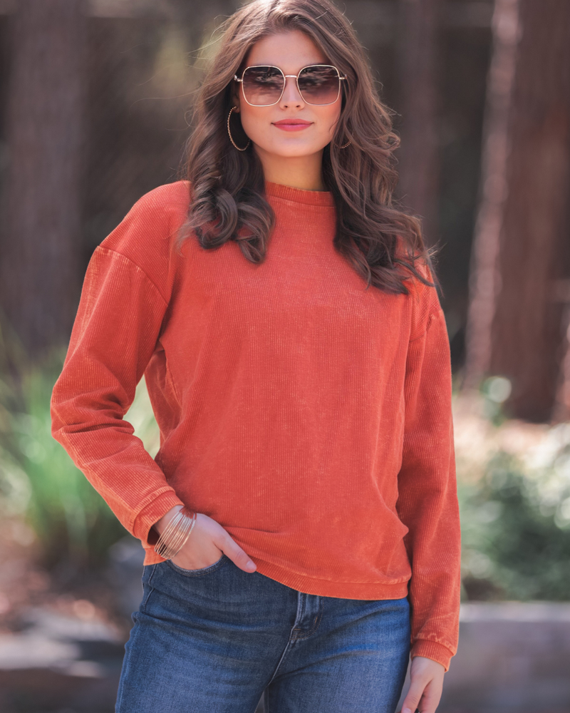 a long-sleeve ribbed textured pullover with a crew neck collar, a vintage wash, and a relaxed fit in rust