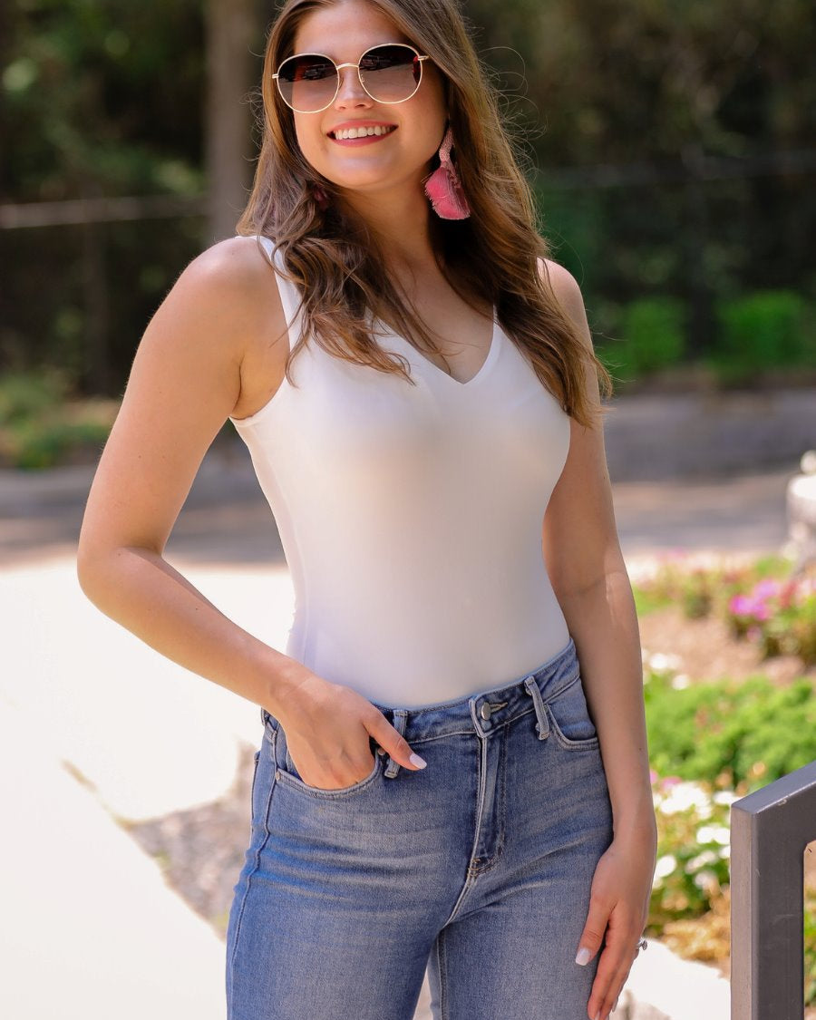one-piece bodysuit made of soft and stretchy lightweight material with a v-neckline, sleeveless shoulder straps with a racerback fit, and a form-fitting silhouette that falls into a cheeky fit with a snap button closure in ivory