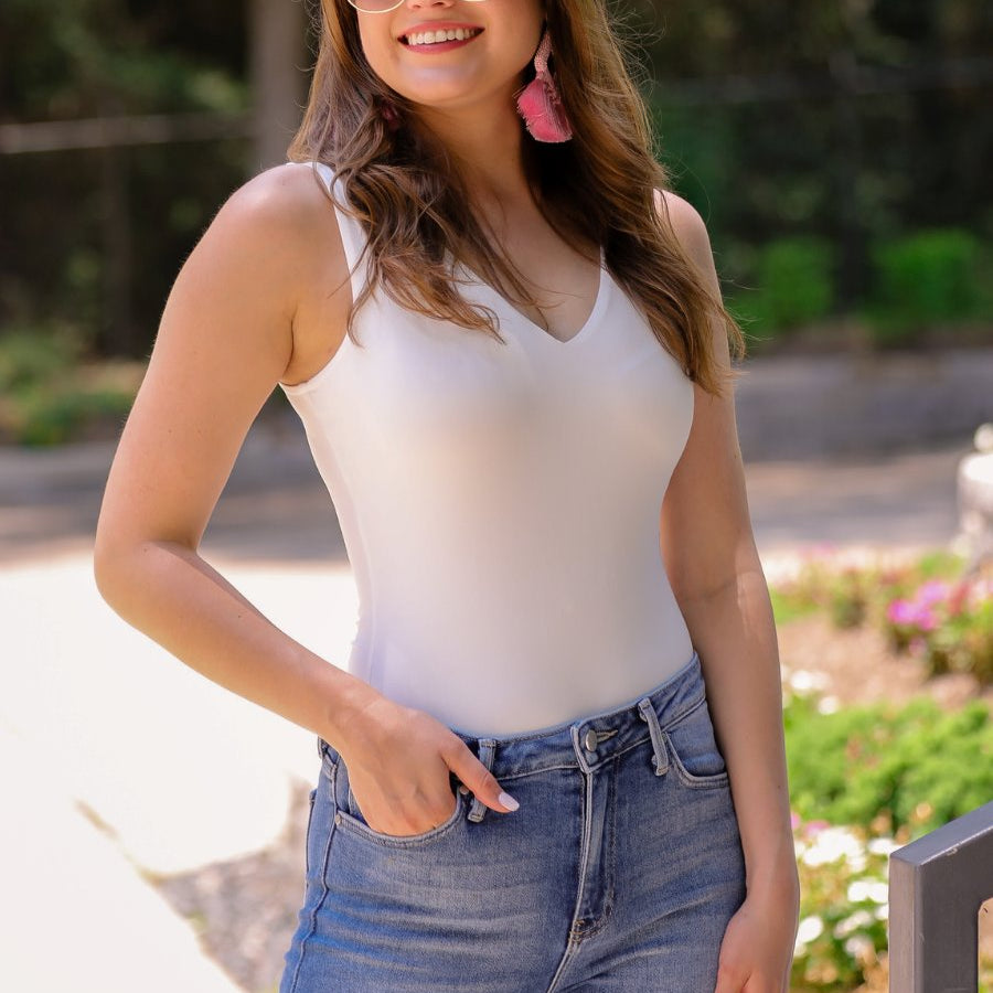 one-piece bodysuit made of soft and stretchy lightweight material with a v-neckline, sleeveless shoulder straps with a racerback fit, and a form-fitting silhouette that falls into a cheeky fit with a snap button closure in ivory