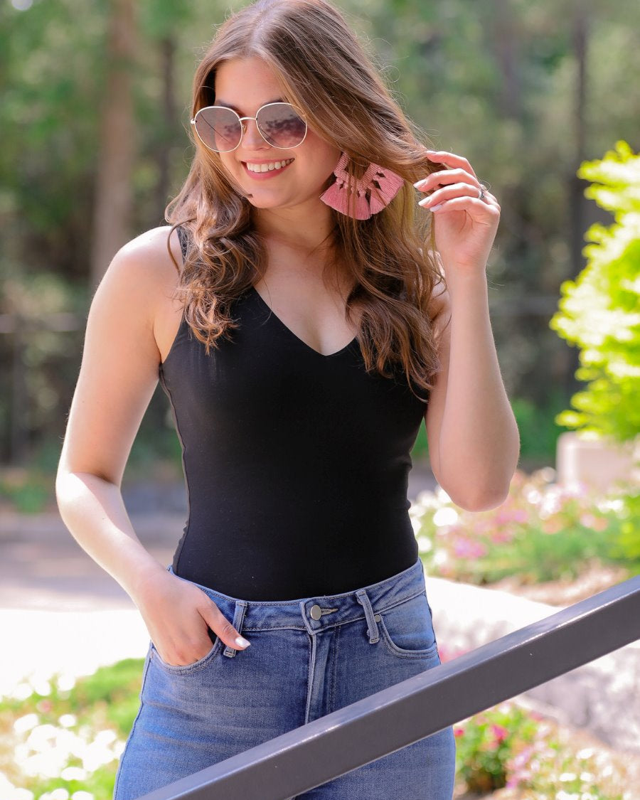 one-piece bodysuit made of soft and stretchy lightweight material with a v-neckline, sleeveless shoulder straps with a racerback fit, and a form-fitting silhouette that falls into a cheeky fit with a snap button closure in black
