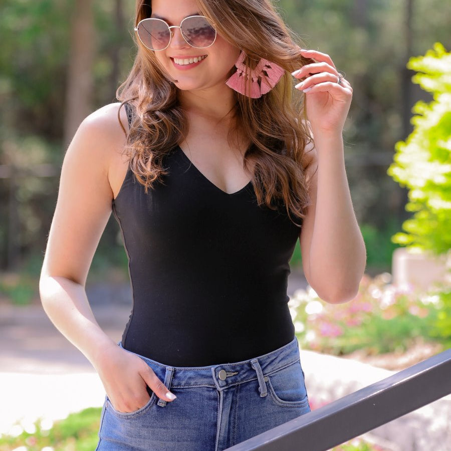 one-piece bodysuit made of soft and stretchy lightweight material with a v-neckline, sleeveless shoulder straps with a racerback fit, and a form-fitting silhouette that falls into a cheeky fit with a snap button closure in black