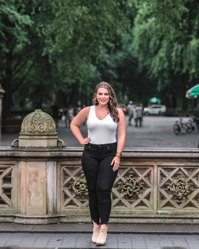 one-piece bodysuit made of soft and stretchy lightweight material with a v-neckline, sleeveless shoulder straps with a racerback fit, and a form-fitting silhouette that falls into a cheeky fit with a snap button closure in ivory