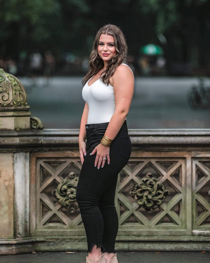 one-piece bodysuit made of soft and stretchy lightweight material with a v-neckline, sleeveless shoulder straps with a racerback fit, and a form-fitting silhouette that falls into a cheeky fit with a snap button closure in ivory