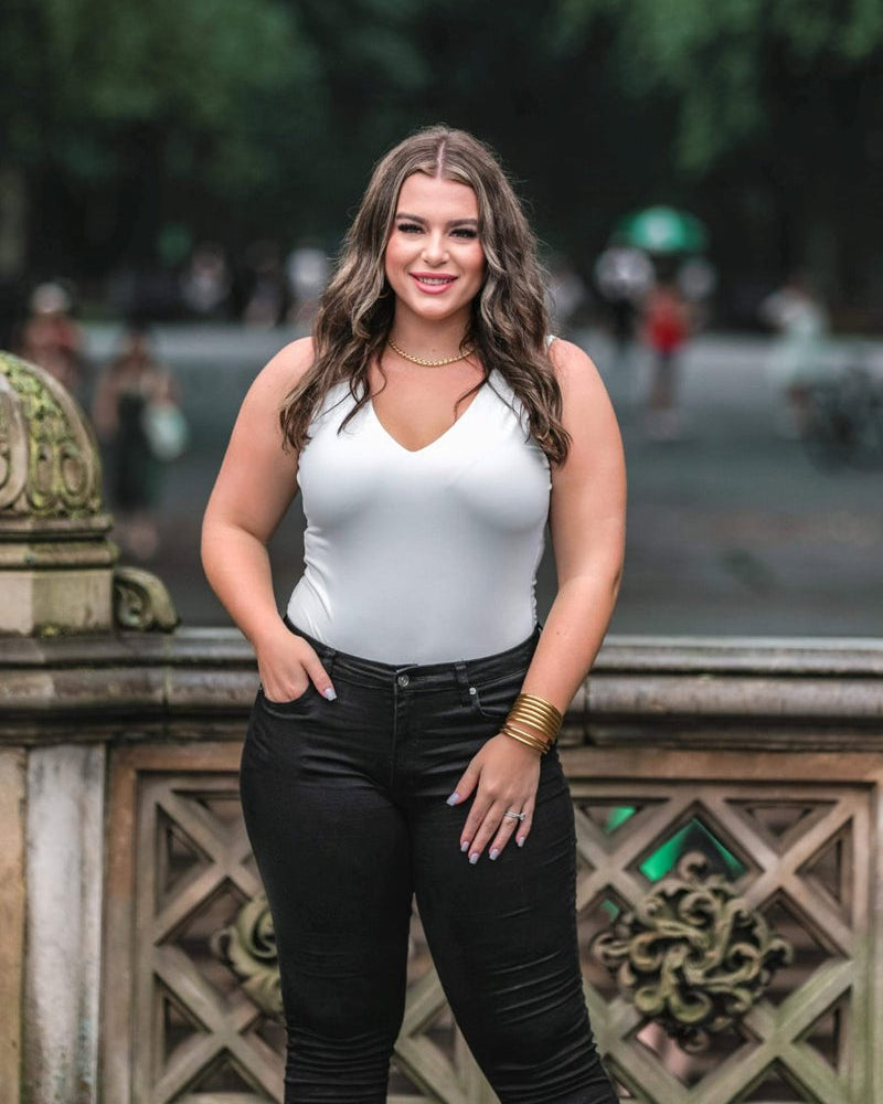 one-piece bodysuit made of soft and stretchy lightweight material with a v-neckline, sleeveless shoulder straps with a racerback fit, and a form-fitting silhouette that falls into a cheeky fit with a snap button closure in ivory