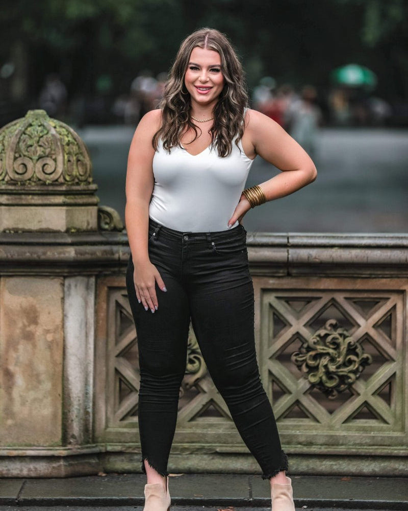 one-piece bodysuit made of soft and stretchy lightweight material with a v-neckline, sleeveless shoulder straps with a racerback fit, and a form-fitting silhouette that falls into a cheeky fit with a snap button closure in ivory