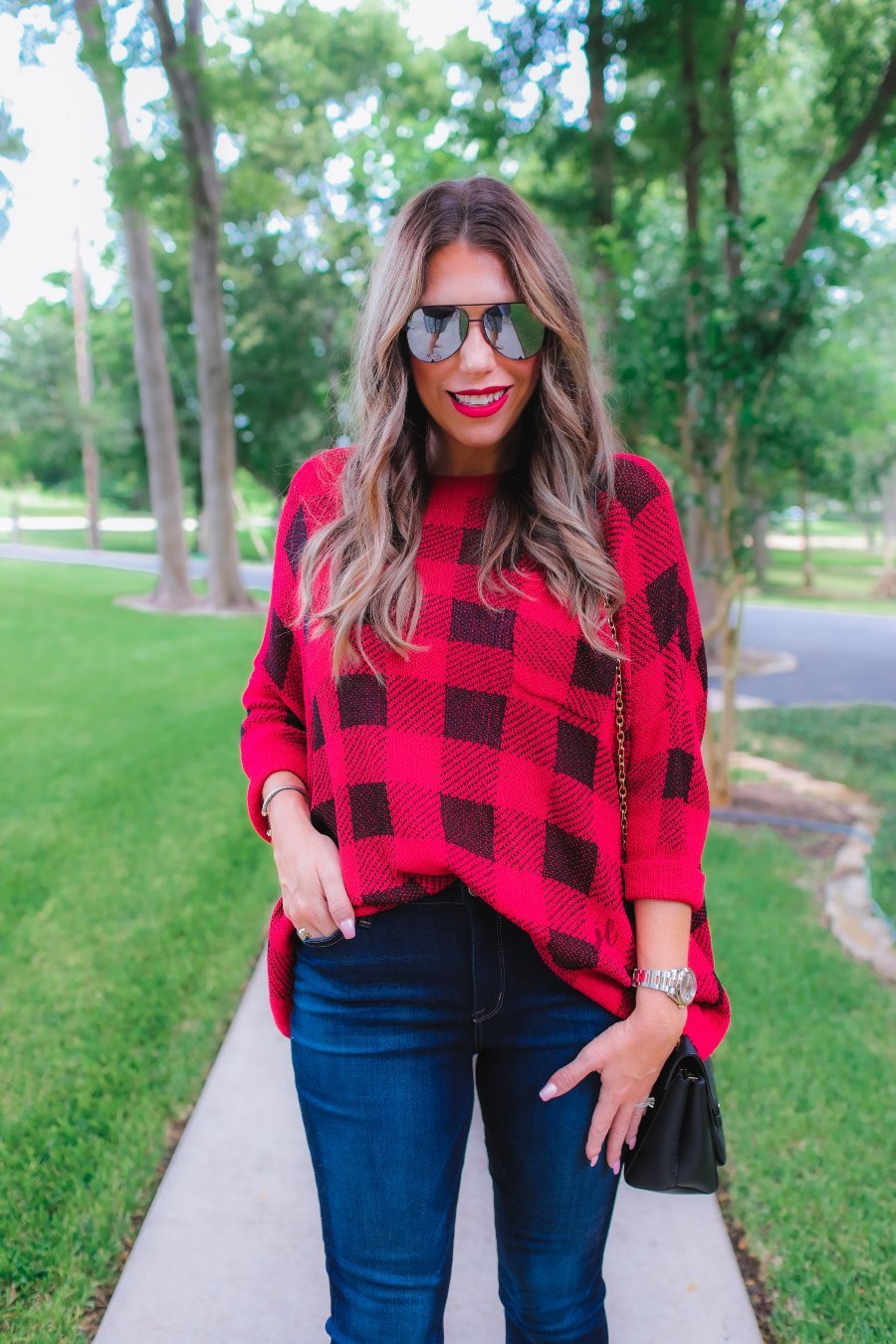 three quarter cuffed sleeve sweater made from unlined loose knit material with a rounded neckline, a chest pocket, and an oversized fit on a black and red plaid pattern