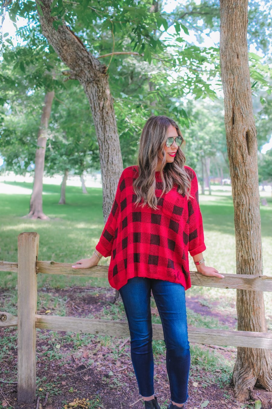 three quarter cuffed sleeve sweater made from unlined loose knit material with a rounded neckline, a chest pocket, and an oversized fit on a black and red plaid pattern
