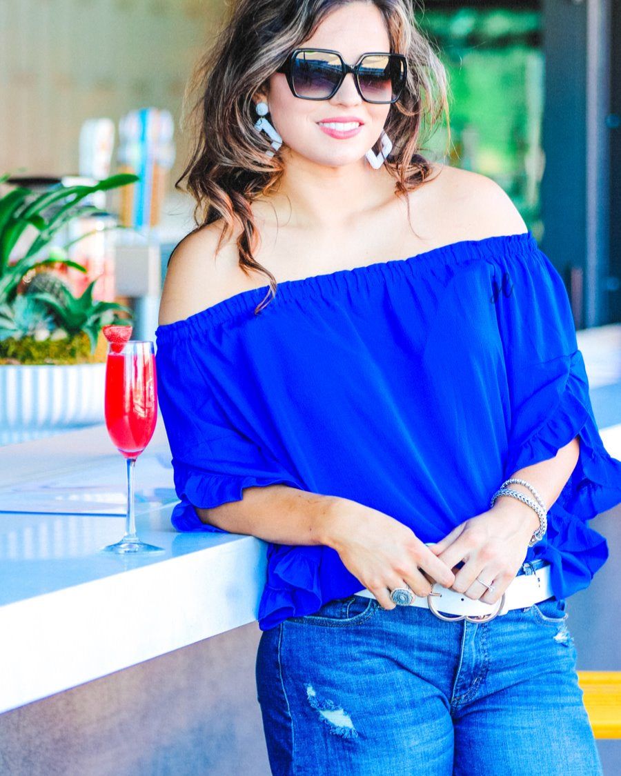 a flowy style top with a gathered scoop neckline that can be worn on or off the shoulder and three-quarter split ruffle sleeves in blue
