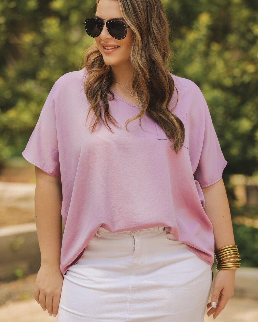a lightweight lilac short-sleeve woven tunic with a V-neckline, a front chest pocket, and a relaxed, non-stretch silhouette