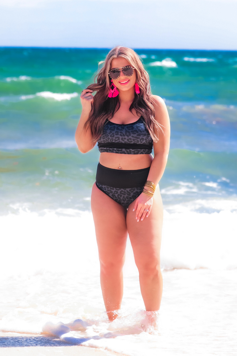 two-piece bikini swimsuit with a scoop neck, adjustable spaghetti straps, and removable padding paired with a full-coverage banded high-waist bottoms on a black leopard print fabric