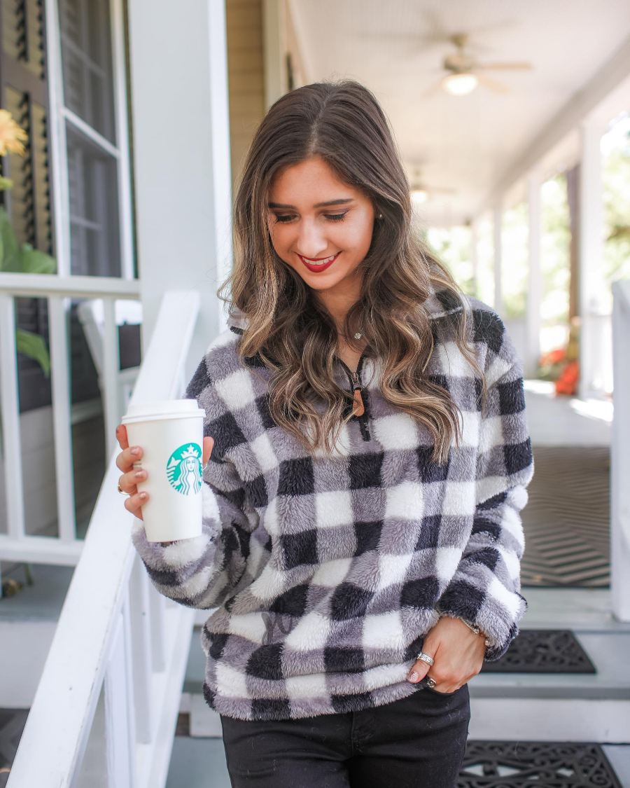 a long-sleeve fluffy pullover with a quarter zip, an adjustable bungee at the hem, and a foldable collar on a classic black and white buffalo plaid pattern fabric