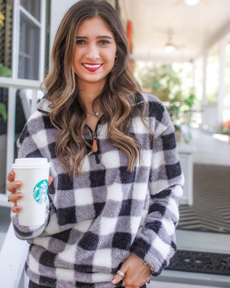 a long-sleeve fluffy pullover with a quarter zip, an adjustable bungee at the hem, and a foldable collar on a classic black and white buffalo plaid pattern fabric