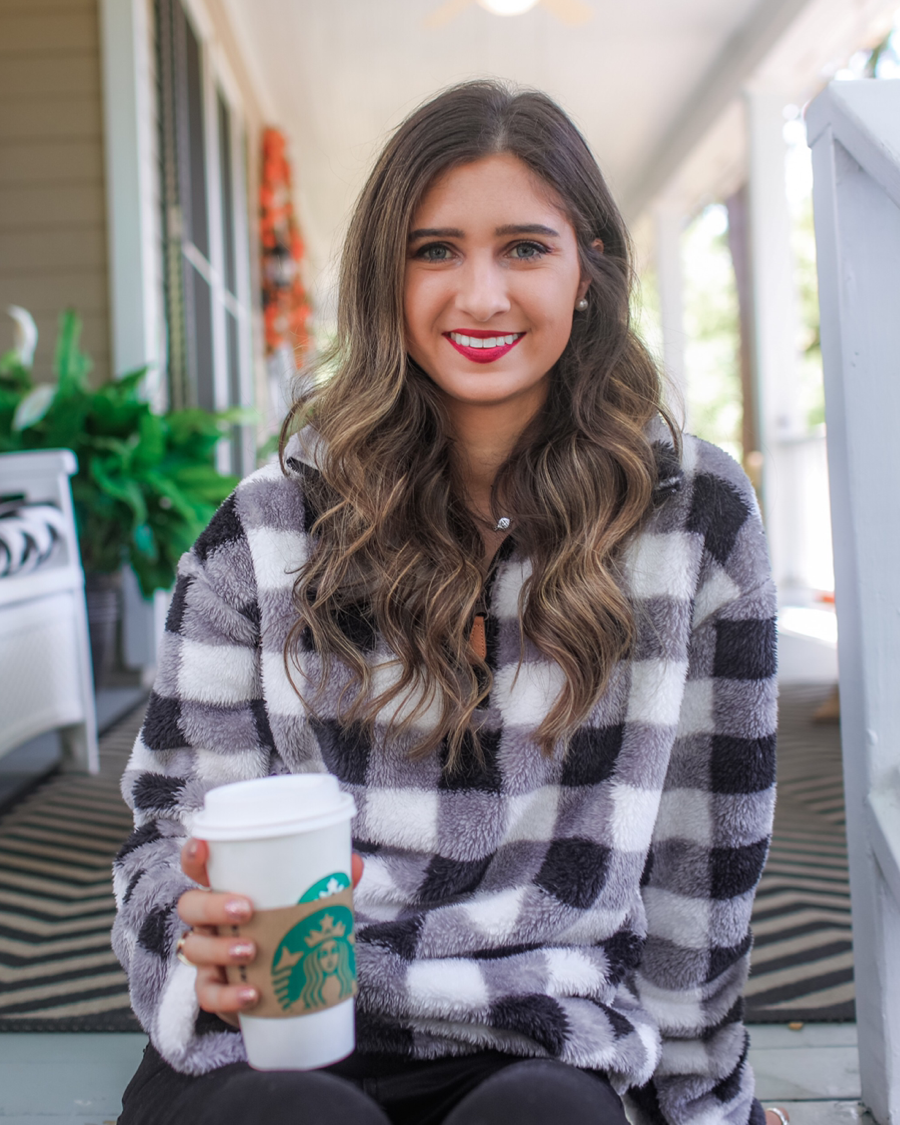 a long-sleeve fluffy pullover with a quarter zip, an adjustable bungee at the hem, and a foldable collar on a classic black and white buffalo plaid pattern fabric