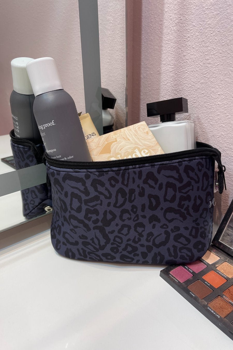 neoprene cosmetic bag in a black on black animal print pattern with dual top zippers (black) and expandable side snaps (silver) on a black on black leopard print pattern