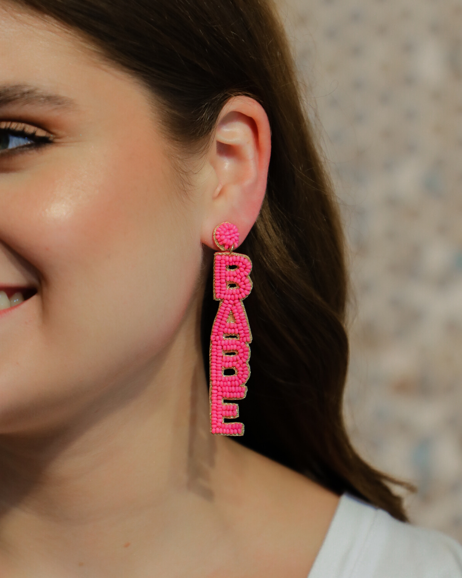 ultra-lightweight hot pink outlined in gold word drop statement earrings highlighting the phrase BOSS (right) and BABE (left) with a post stud, felt backing, comfort replacement backs, and gold-tone plastic disk stopper