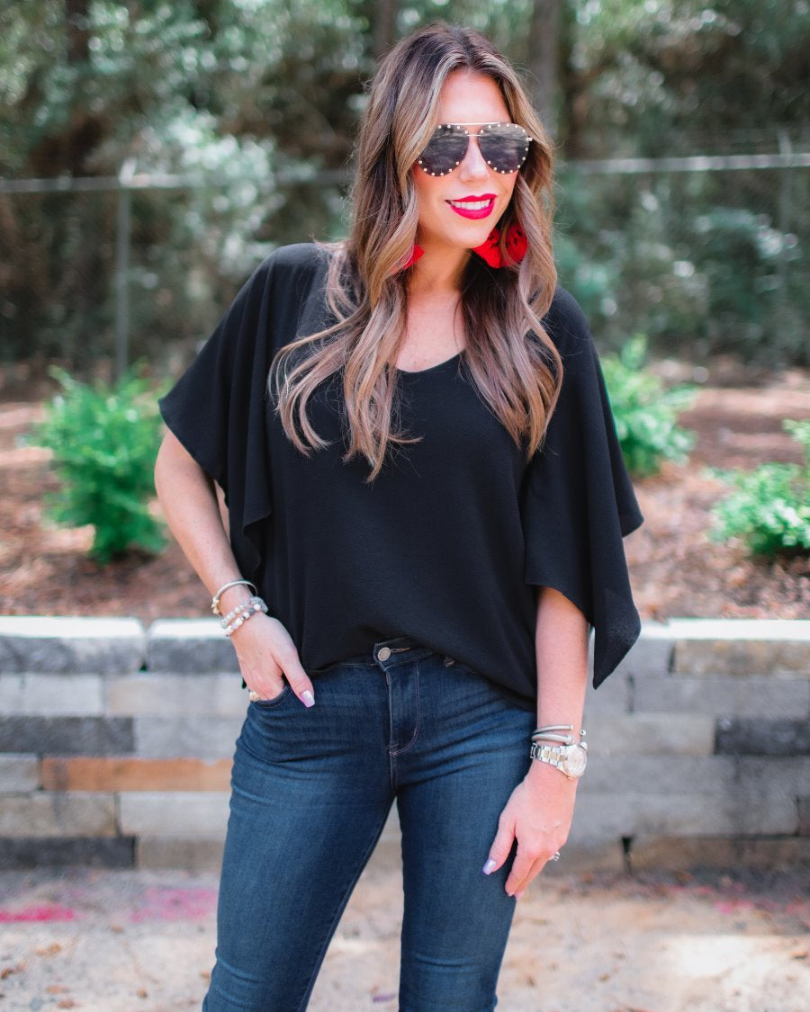 a black v-neck blouses crafted from lightweight textured fabric with asymmetrical half-flutter sleeves, front lining, and a relaxed fit