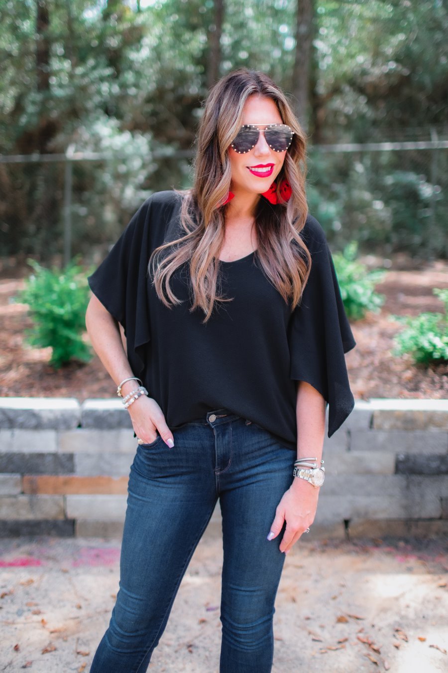 a black v-neck blouses crafted from lightweight textured fabric with asymmetrical half-flutter sleeves, front lining, and a relaxed fit
