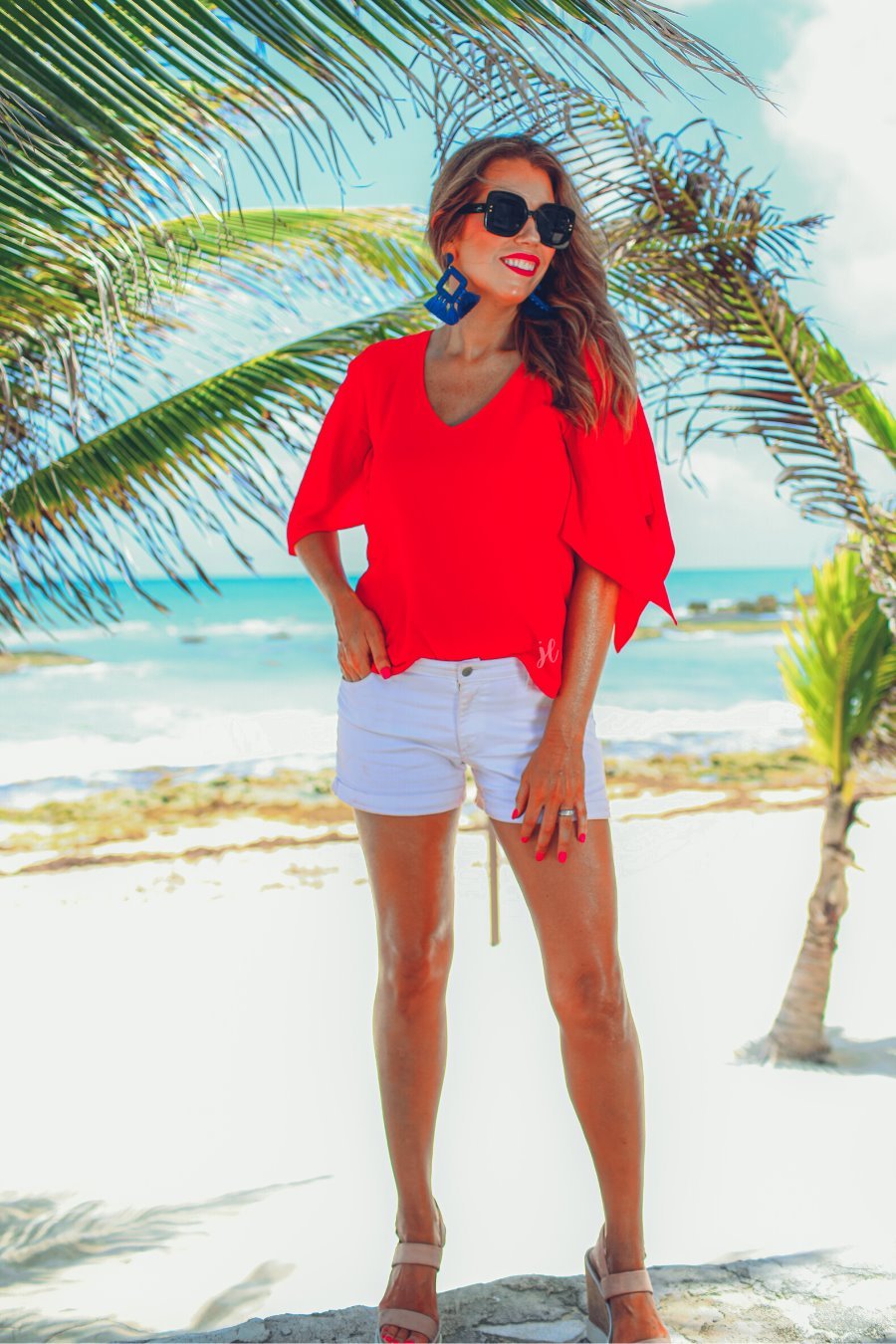 a red v-neck blouses crafted from lightweight textured fabric with asymmetrical half-flutter sleeves, front lining, and a relaxed fit, accented by a MADE IN USA watermark in the bottom left-hand corner