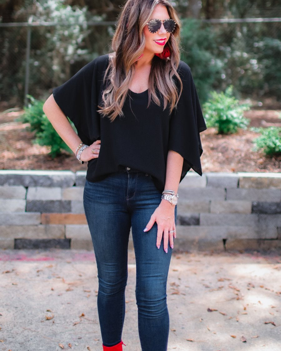 a black v-neck blouses crafted from lightweight textured fabric with asymmetrical half-flutter sleeves, front lining, and a relaxed fit