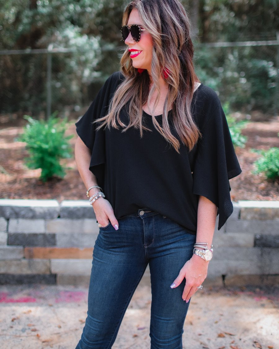 a black v-neck blouses crafted from lightweight textured fabric with asymmetrical half-flutter sleeves, front lining, and a relaxed fit