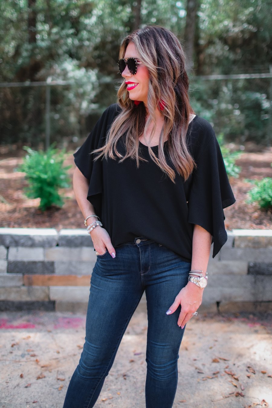 a black v-neck blouses crafted from lightweight textured fabric with asymmetrical half-flutter sleeves, front lining, and a relaxed fit