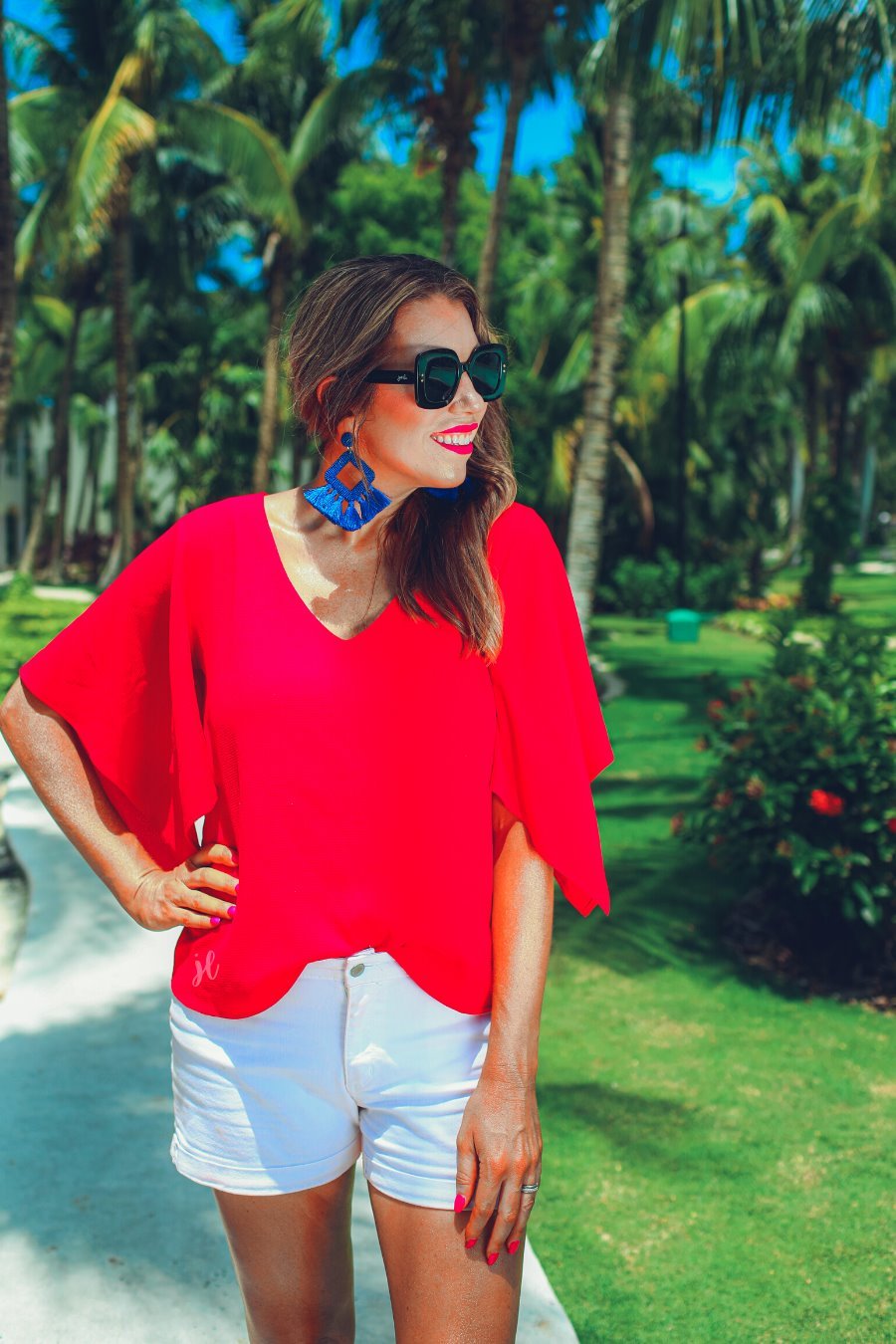 a red v-neck blouses crafted from lightweight textured fabric with asymmetrical half-flutter sleeves, front lining, and a relaxed fit, accented by a MADE IN USA watermark in the bottom left-hand corner