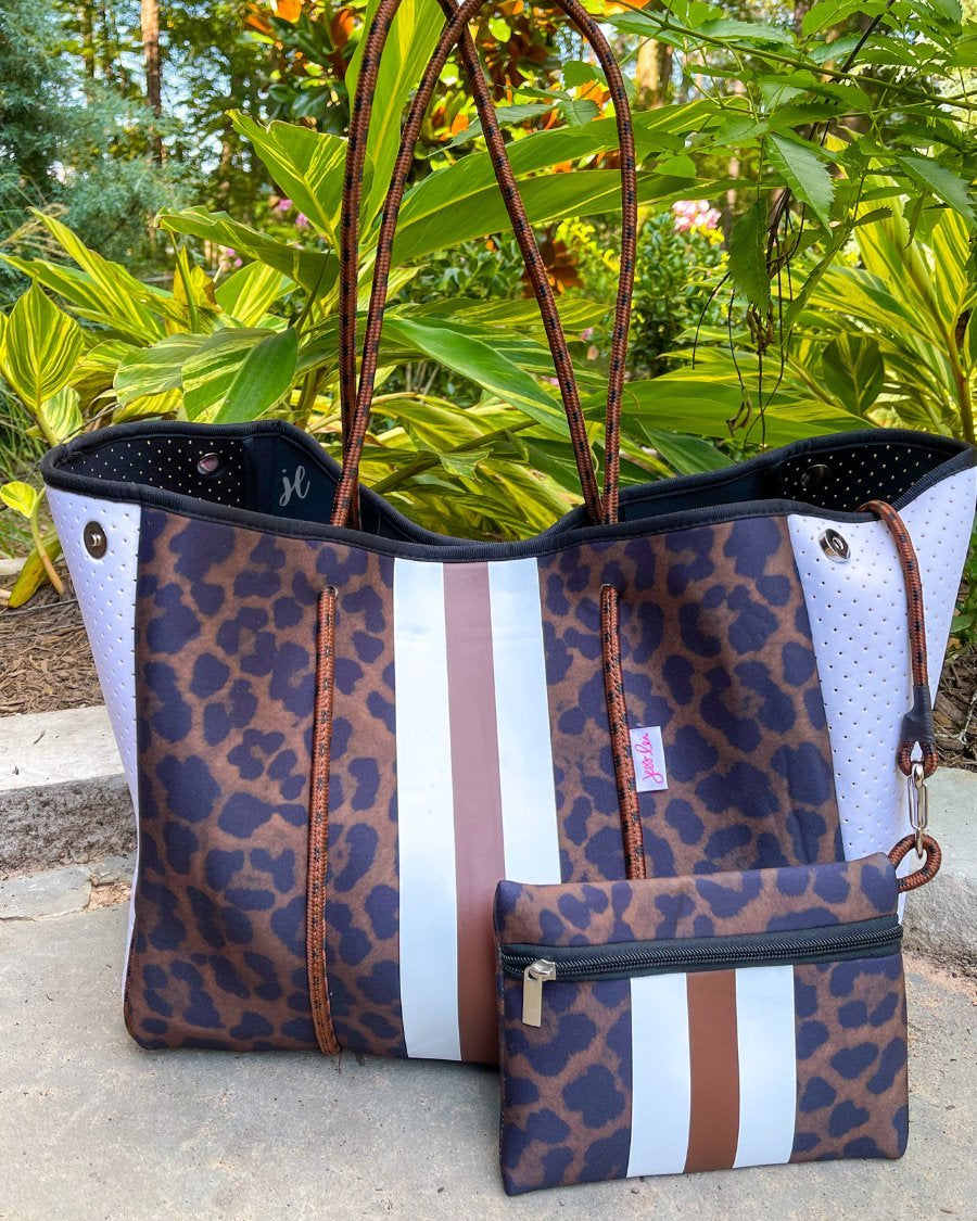 ultra-lightweight tote made of neoprene with a removable hard bottom liner, paracord shoulder straps, removable matching zippered pouch, magnetic side snap closures in silver hardware, black interior (tote and pouch), and racing stripes (brown and white) on a black and brown leopard print pattern