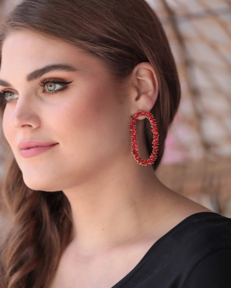 gold cubic zirconia earrings secured with a push backing in a long oval shape in red