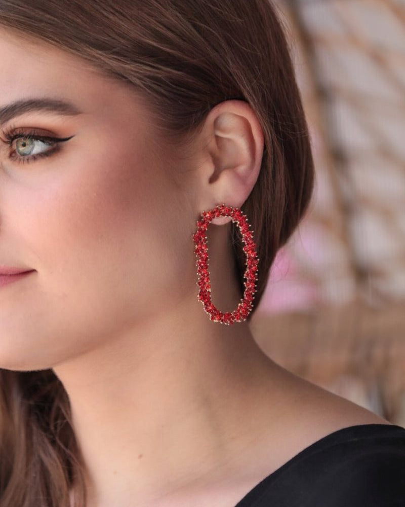 gold cubic zirconia earrings secured with a push backing in a long oval shape in red