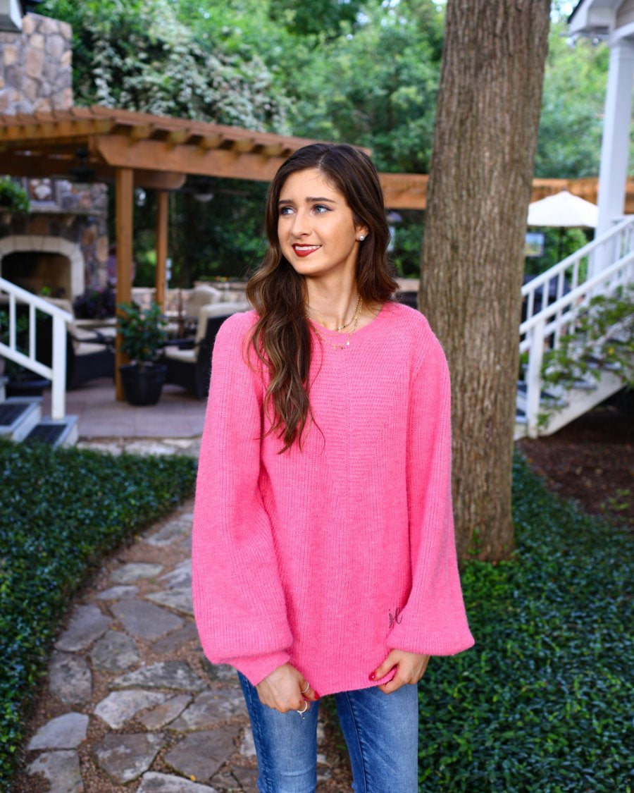 a pink soft knit long-sleeve sweater with a classic rounded neckline, statement balloon sleeves, and ribbed detailing at the cuffs and hemline