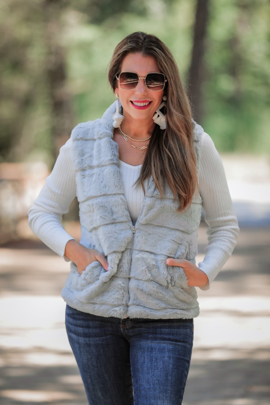 a sleeveless faux fur vest with a foldable collar, a front zip, sublte horizontal paneling, and front pockets made of super soft fabric that fits slightly oversized in grey