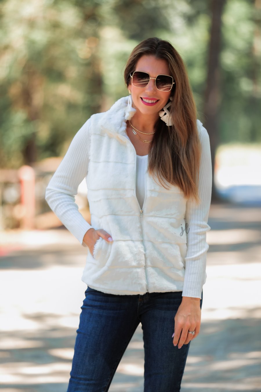 a sleeveless faux fur vest with a foldable collar, a front zip, sublte horizontal paneling, and front pockets made of super soft fabric that fits slightly oversized in white
