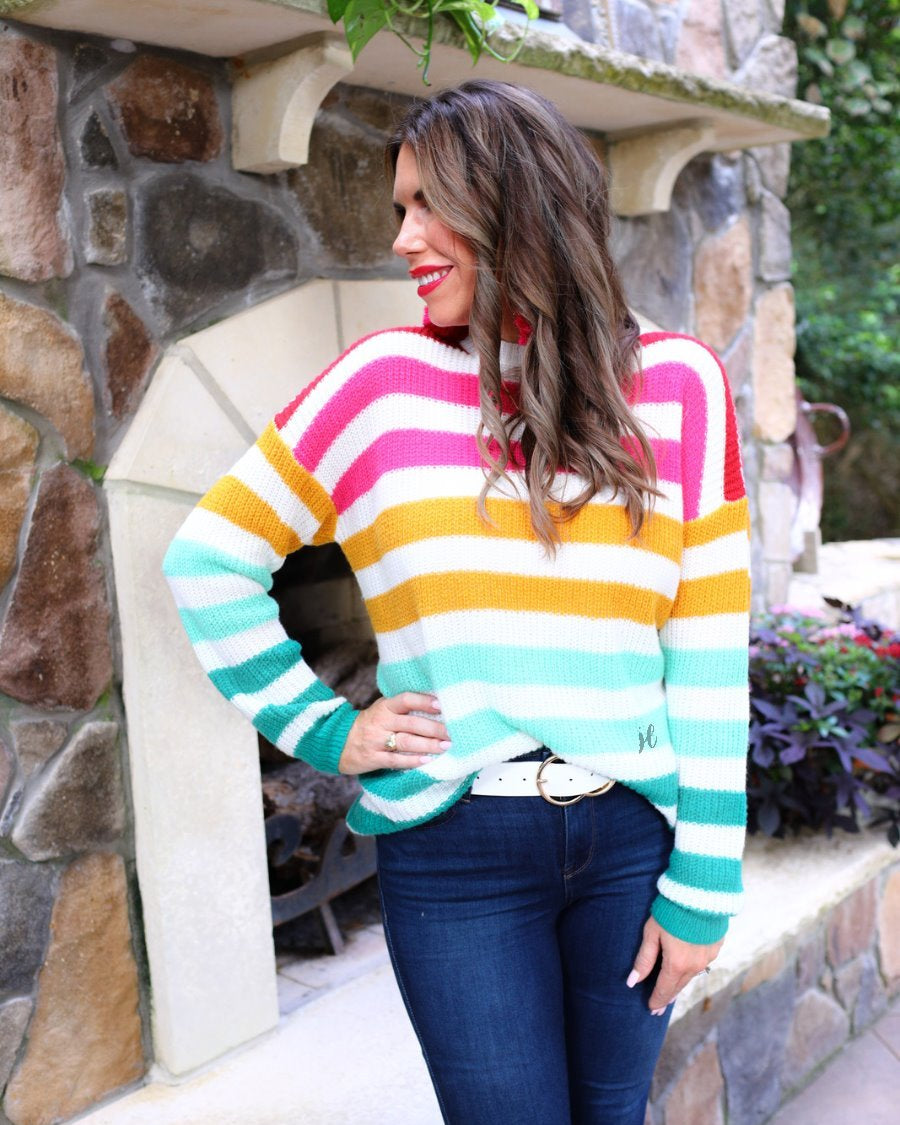 a textured knit long-sleeve sweater with a vibrant colorful stripe pattern (burgundy, magenta, mustard, teal, and forest green), a relaxed drop-shoulder fit, classic crew neckline, and ribbed detailing on the cuffs, neckline, and hemline on an ivory base