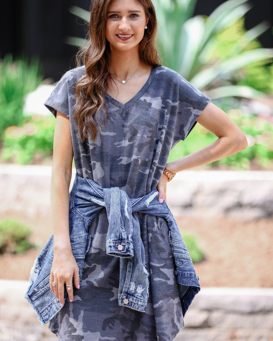an oversized grey A-line pocket dress with a V-neckline, short sleeves, side pockets, a curved hem, and a terry cloth texture