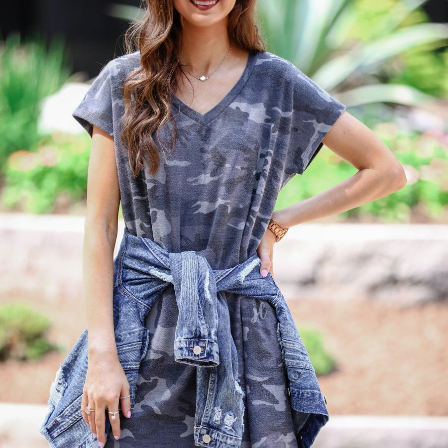 an oversized grey A-line pocket dress with a V-neckline, short sleeves, side pockets, a curved hem, and a terry cloth texture
