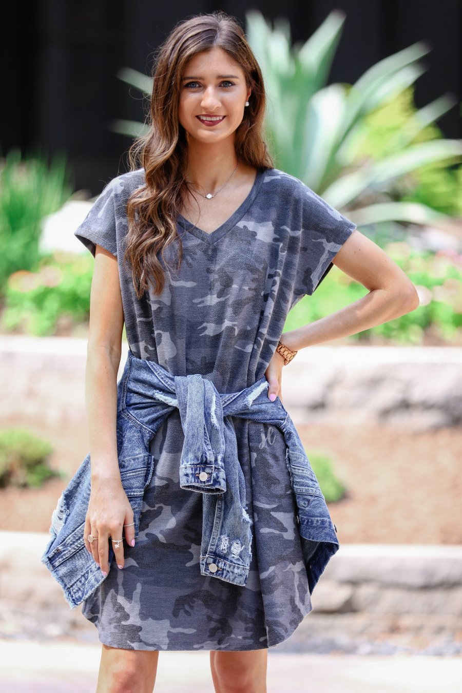 an oversized grey A-line pocket dress with a V-neckline, short sleeves, side pockets, a curved hem, and a terry cloth texture