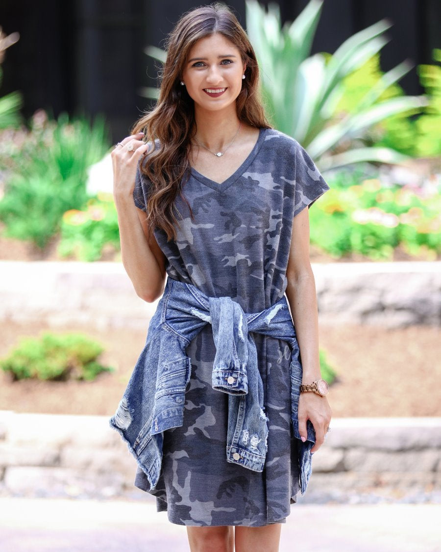 an oversized grey A-line pocket dress with a V-neckline, short sleeves, side pockets, a curved hem, and a terry cloth texture