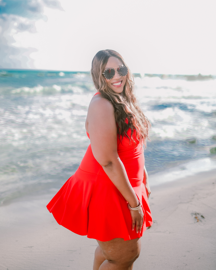 solid red halter swimsuit with a mesh v-neckline leading to a back clasp closure, skirted hem, attached full coverage bottoms, and removable padding