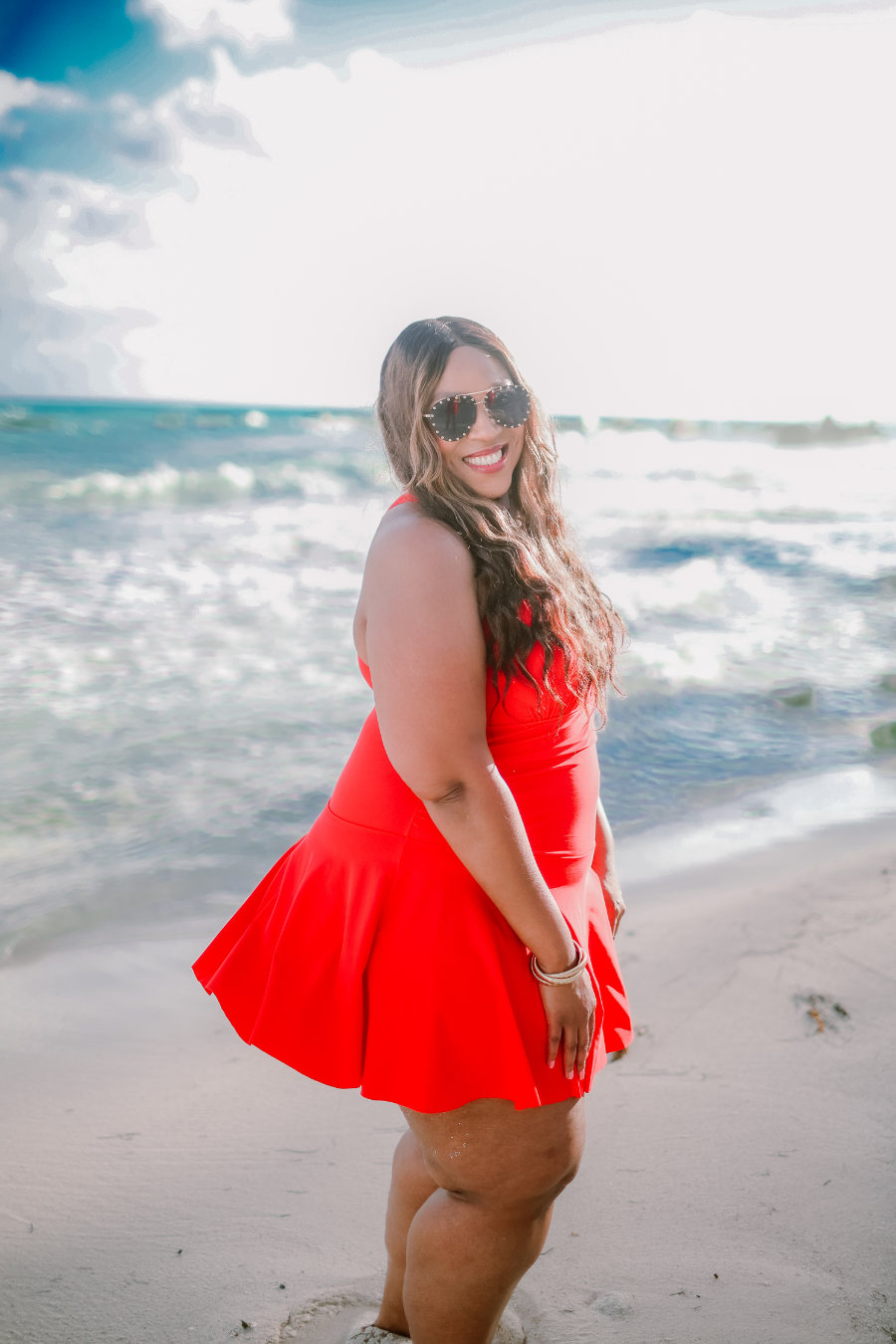 a solid red one-piece swimsuit with a halter neckline, sheer mesh V-detail, secure back clasp, removable padding, skirted hem, and attached full-coverage bottoms