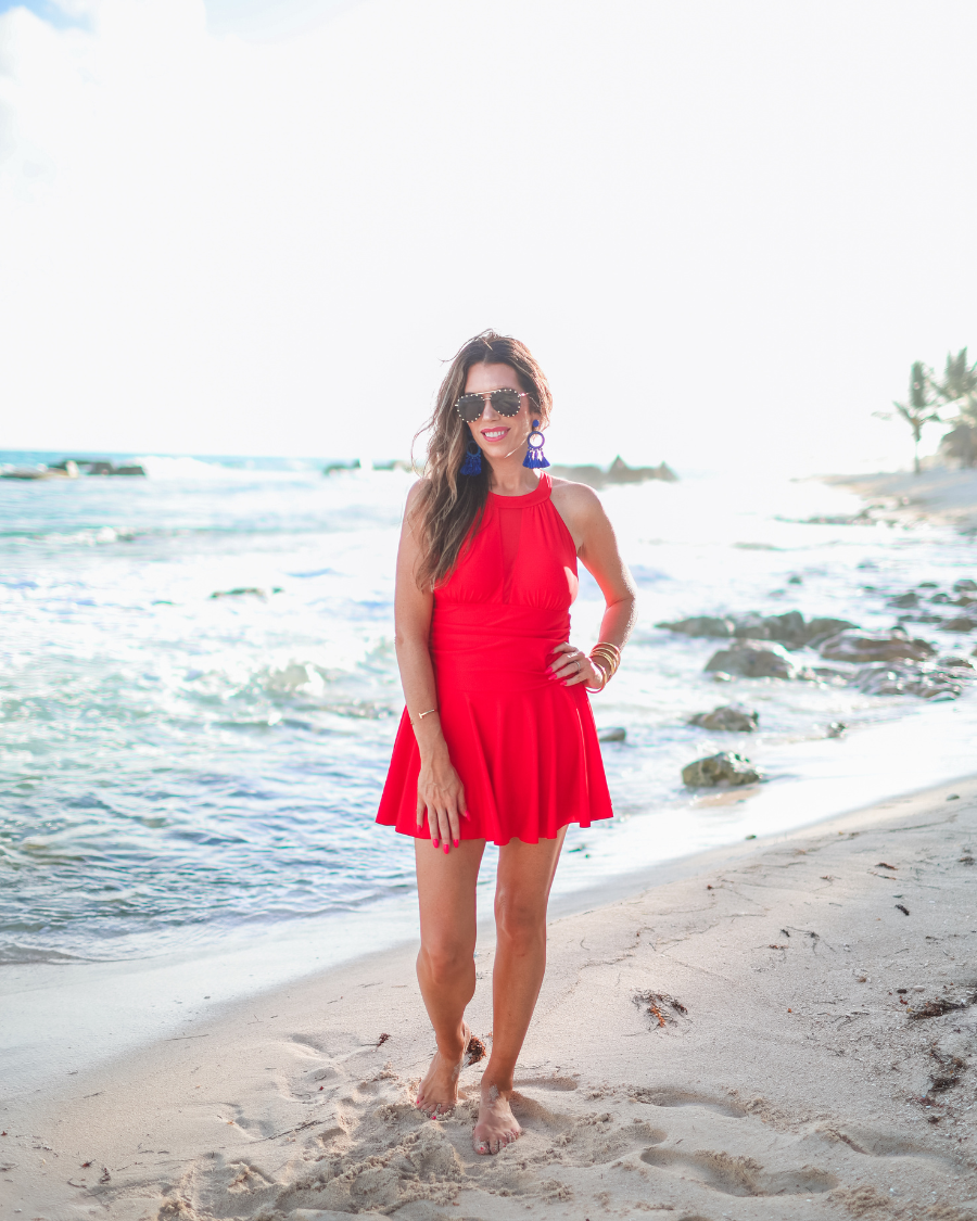 solid red halter swimsuit with a mesh v-neckline leading to a back clasp closure, skirted hem, attached full coverage bottoms, and removable padding