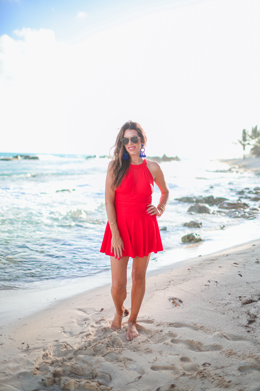 a solid red one-piece swimsuit with a halter neckline, sheer mesh V-detail, secure back clasp, removable padding, skirted hem, and attached full-coverage bottoms