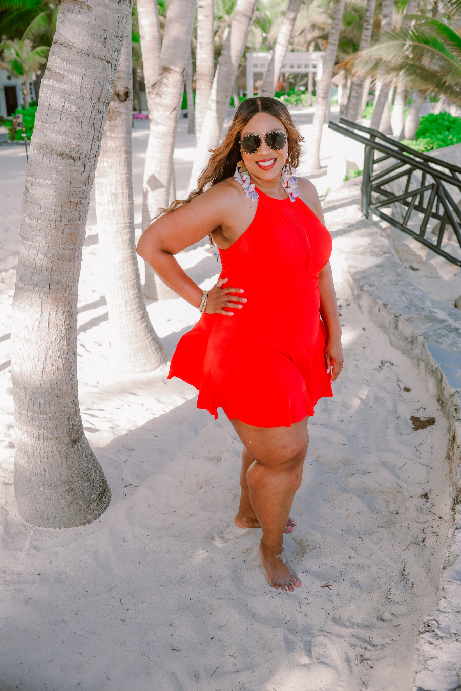 a solid red one-piece swimsuit with a halter neckline, sheer mesh V-detail, secure back clasp, removable padding, skirted hem, and attached full-coverage bottoms