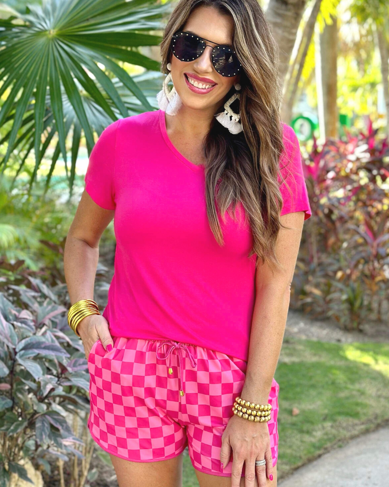 mid-rise relaxed fit activewear shorts with side pockets and a tie waist drawstring with gold bead accents, designed on a two-tone pink checkered pattern print fabric and pink trim